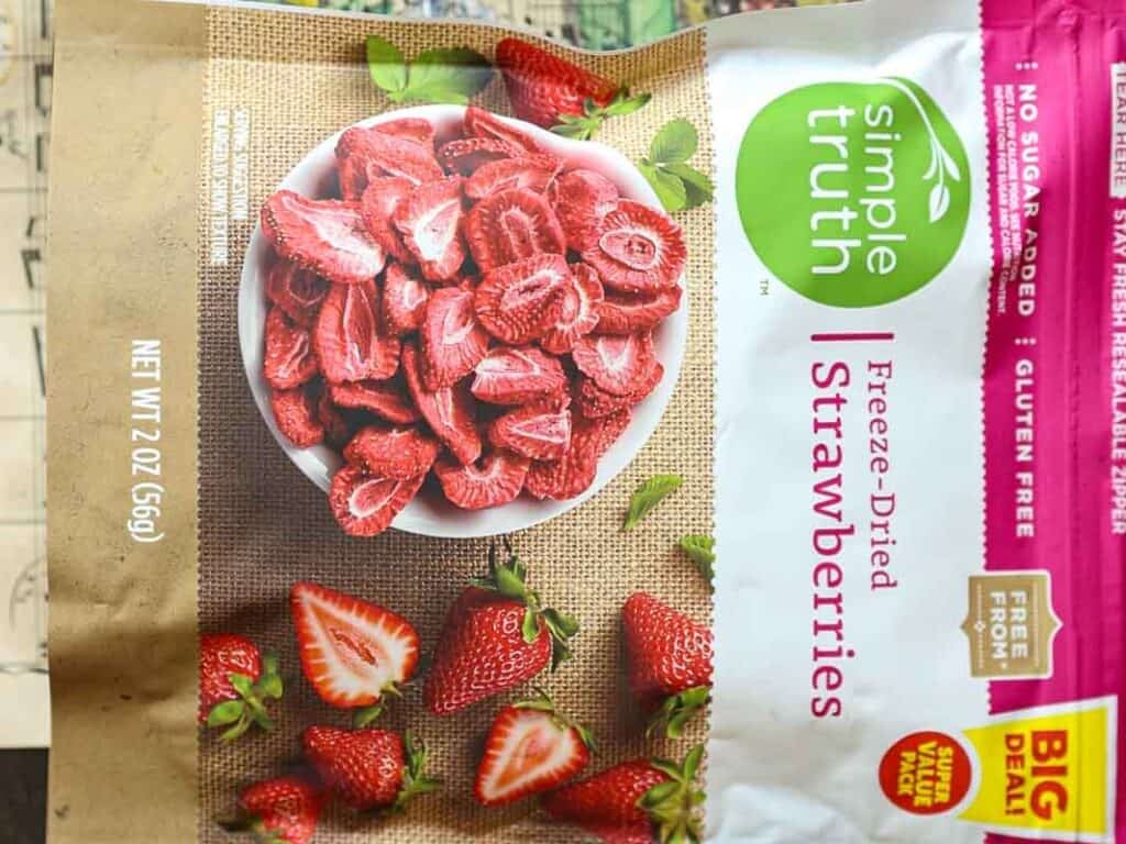 A package of Simple Truth Freeze-Dried Strawberries. The front displays a bowl filled with sliced strawberries, alongside whole strawberries on a burlap surface. The package is labeled as gluten-free and contains 2 ounces (56g).